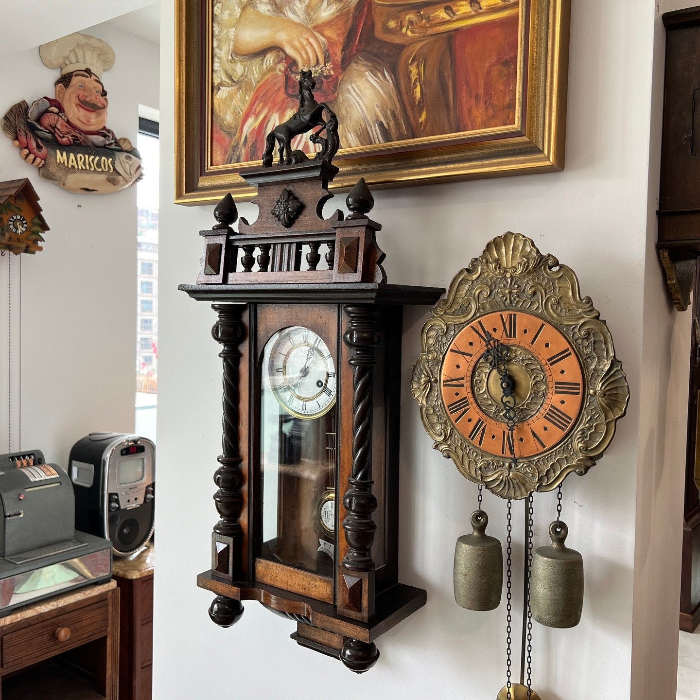 Antique solid wood wall clock in perfect condition hanging on a wall with other vintage decor items